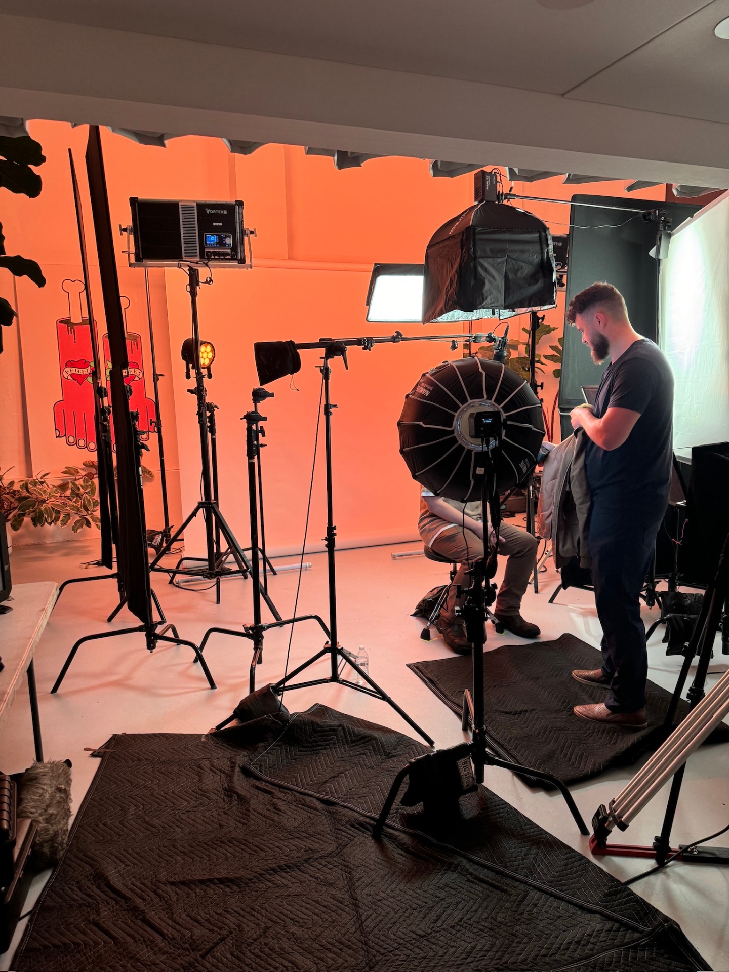 Orange-lit studio with cinema lights and softboxes on set