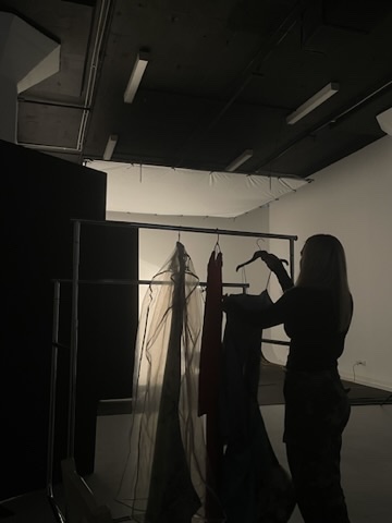 Silhouette of styling prep beside a garment rack