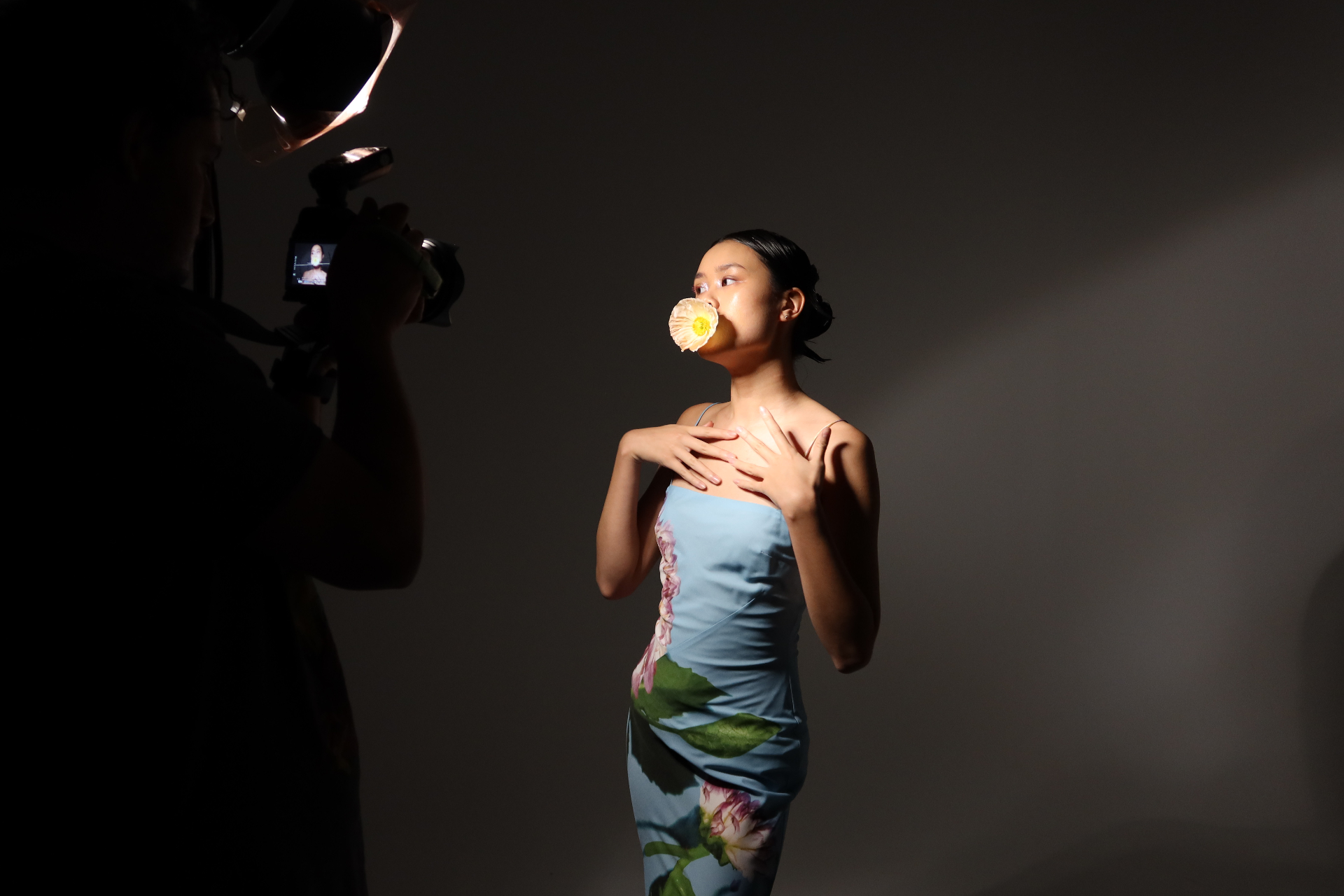 Photographer capturing a model lit in profile with a flower